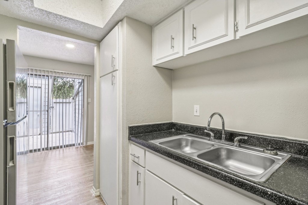 a kitchen with white cabinets and a sink and a window