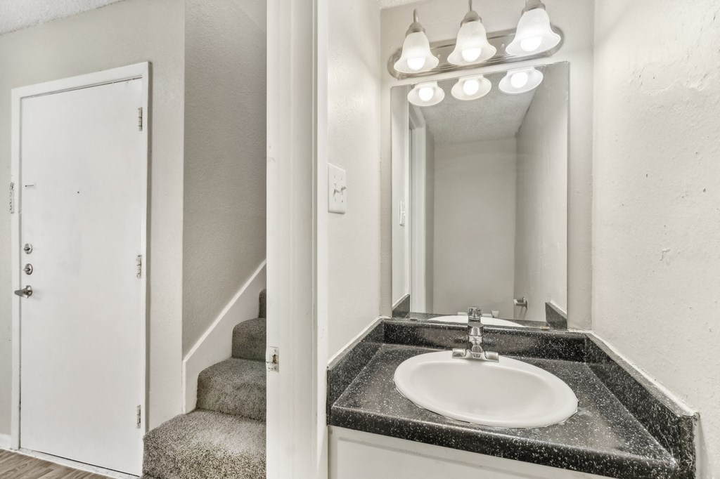 a bathroom with a sink and a mirror and a staircase