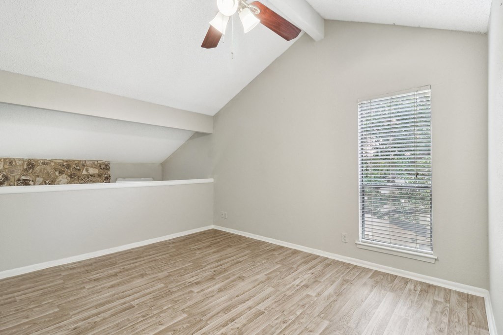 a bedroom with a large window and wood flooring