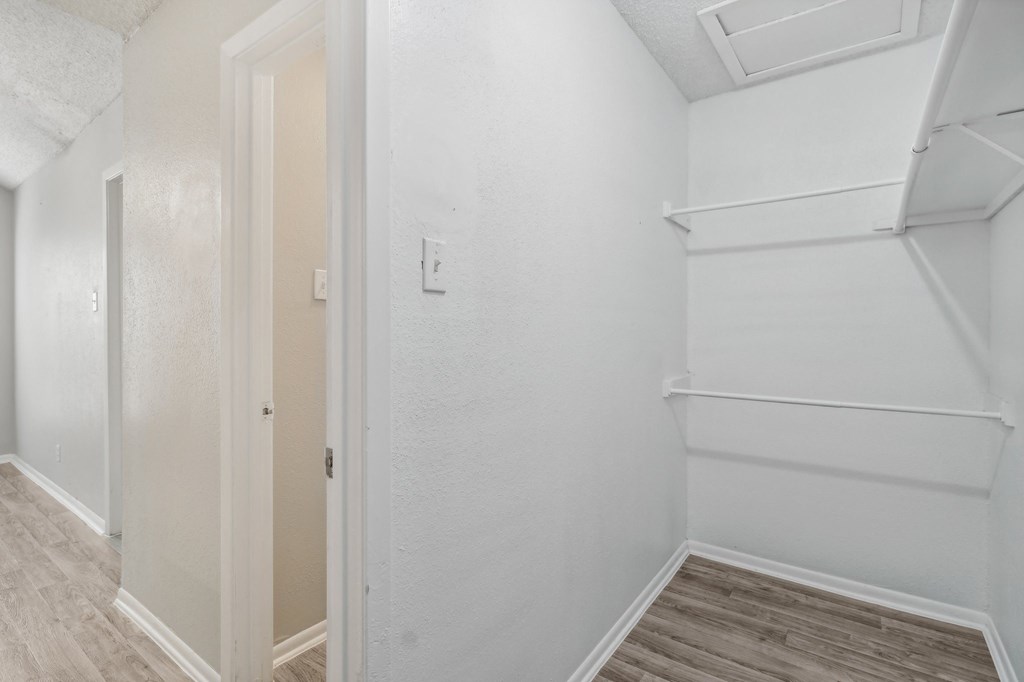 A walk-in closet of our A7 apartment The Escapade with white walls and wood flooring