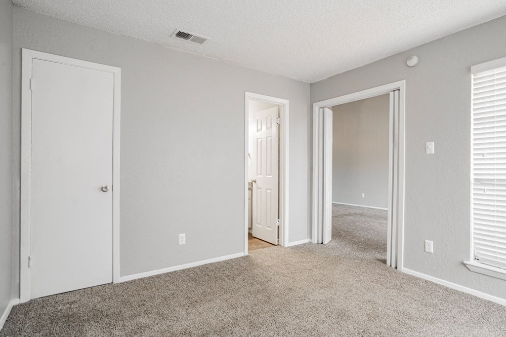 an empty bedroom with white doors and a carpeted floor
