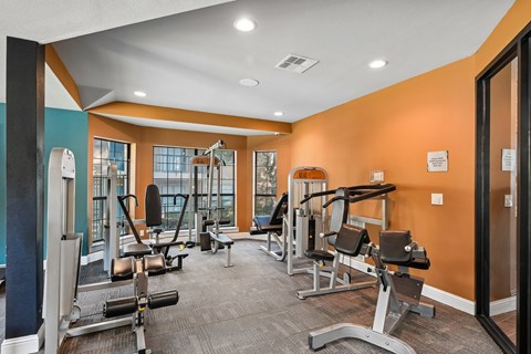 A gym with orange walls and a variety of exercise equipment.