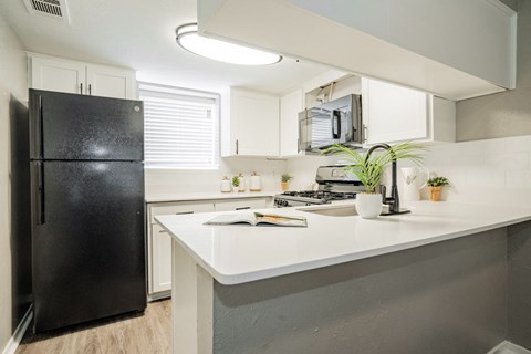 A black fridge sits next to a white counter in a kitchen.