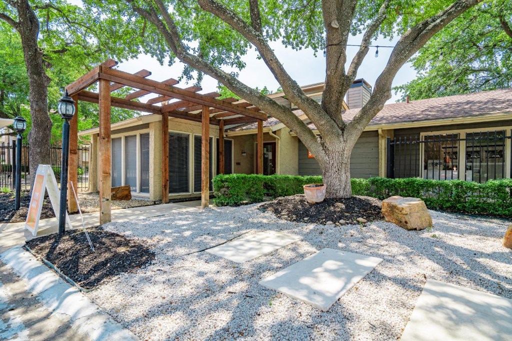 a patio with a tree in front of a house