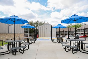 a picnic area with tables and umbrellas in front of a building at Aero White Rock, Dallas, 75238