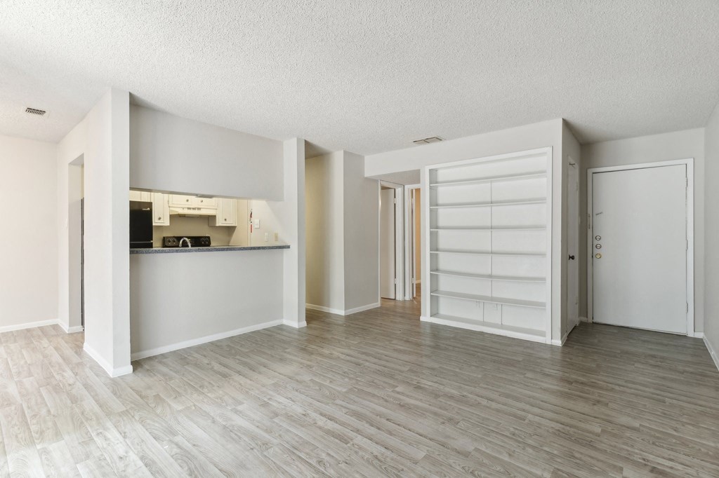 the living room and kitchen of a renovated apartment with white walls and wood floors
