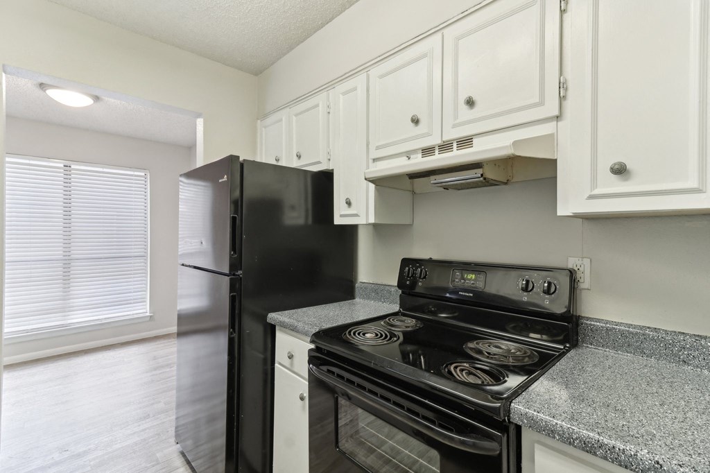 The Escapade apartment kitchen with black stove and refrigerator