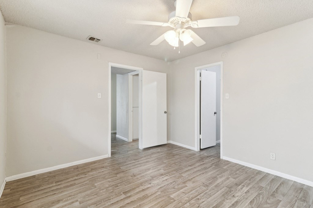 a spacious bedroom with white walls and a ceiling fan