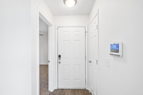 A hallway with a white door and a monitor on the wall.