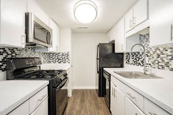 a kitchen with white cabinets and black appliances at Aero White Rock, Dallas