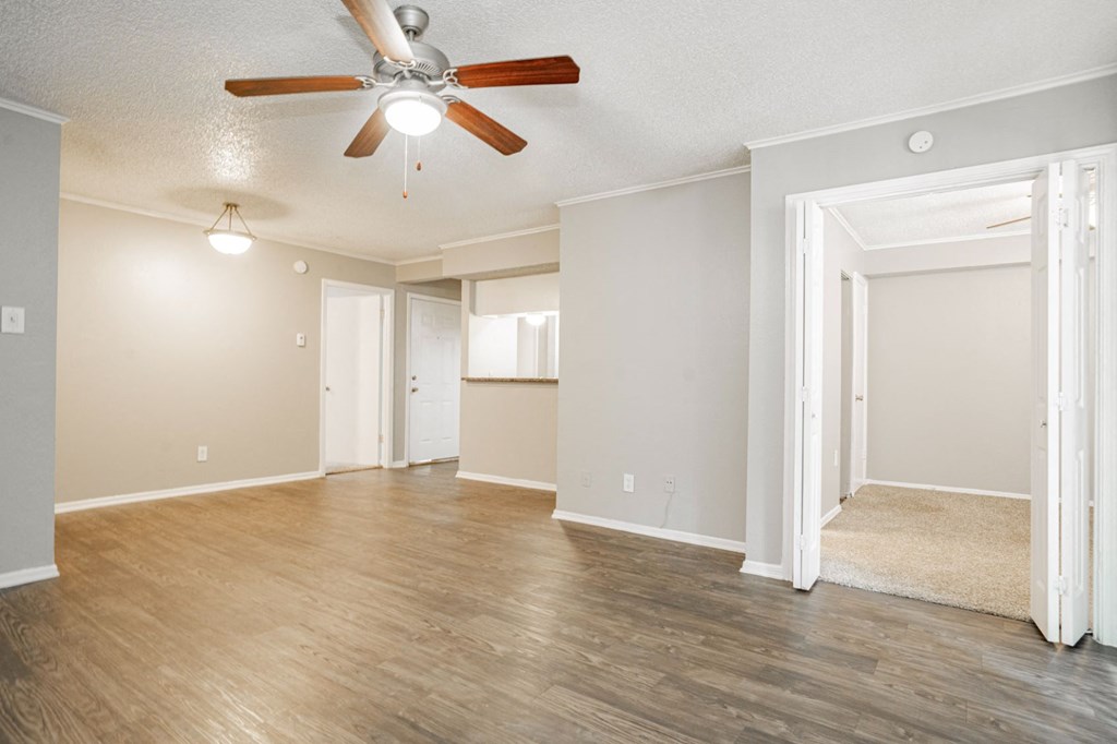 an empty living room with wood floors and a ceiling fan
