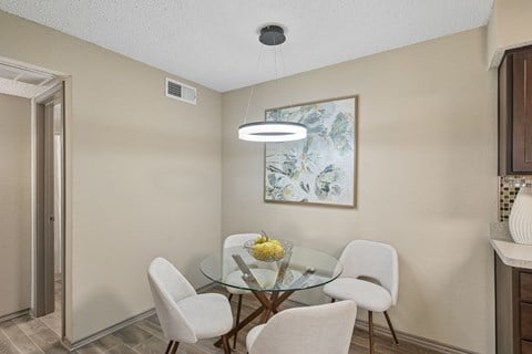 A dining room with a glass table and white chairs.