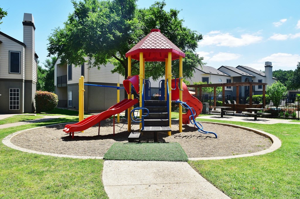 A playground with a red slide and a yellow and red playhouse.