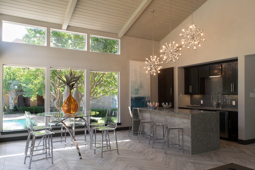 a dining area with a glass table and chairs and a kitchen with a large window