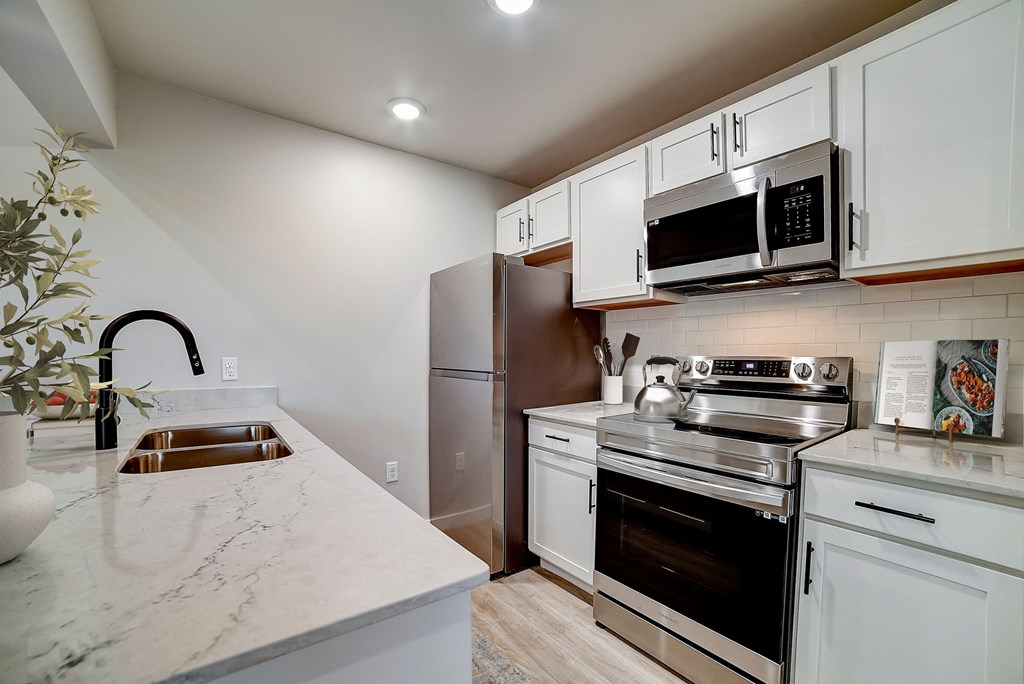 a kitchen with white cabinets and stainless steel appliances at The Frederick, San Antonio, 78240