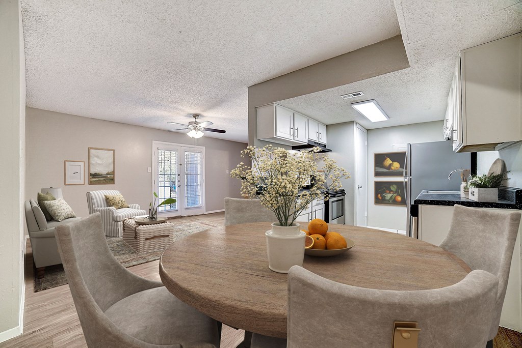 a dining room with a table and chairs and a kitchen with a refrigerator and stove