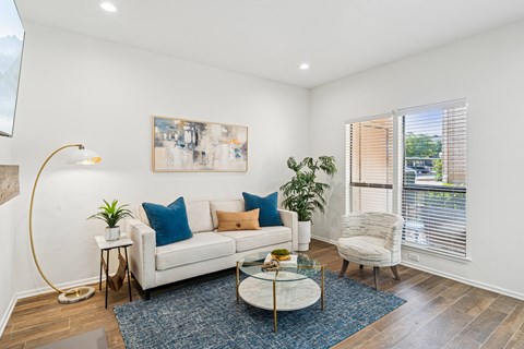 A living room with a white couch, a coffee table, and a painting on the wall.