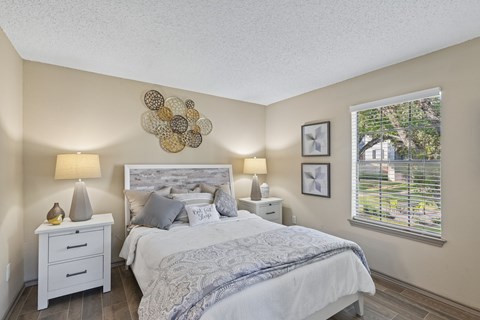 A bedroom with a large bed and two lamps.