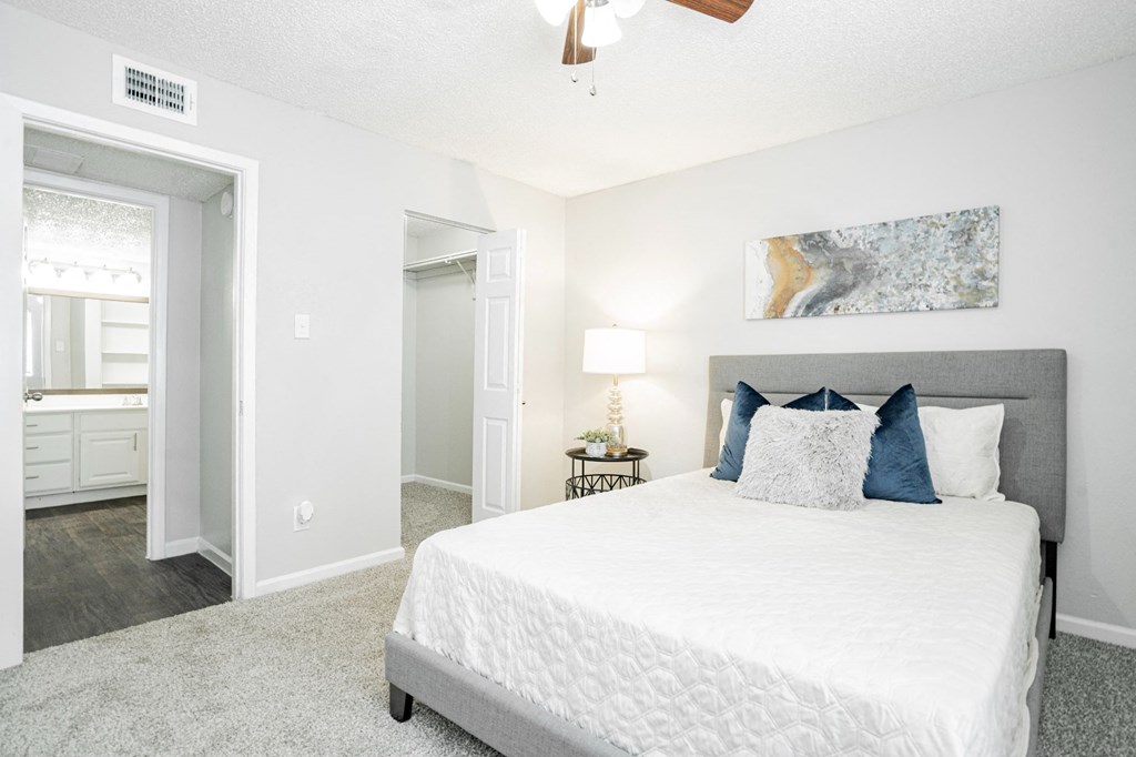 a bedroom with a large white bed and a ceiling fan
