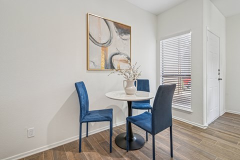 Dining area with round table and blue upholstered chairs at Hidden Ridge Apartments, Irving