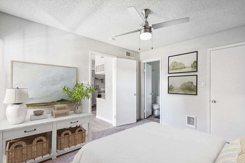 a bedroom with a white bed and a ceiling fan