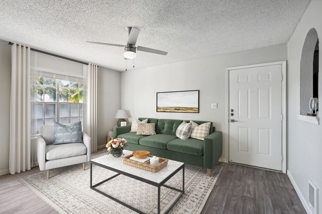 a living room with a green couch and a ceiling fan