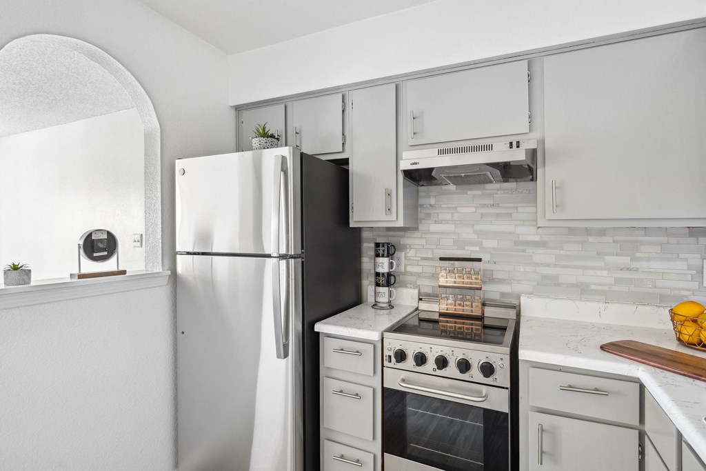 a kitchen with white cabinets and appliances and a refrigerator