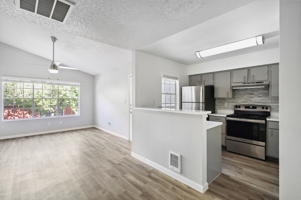 an empty apartment with a kitchen and a large window