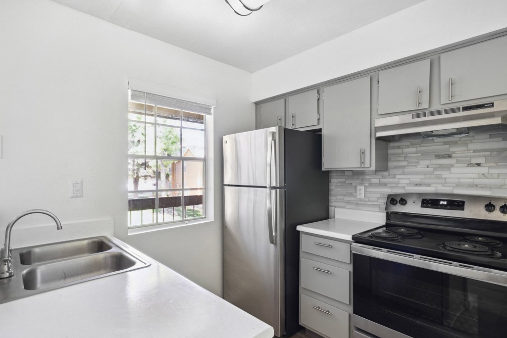 an empty kitchen with stainless steel appliances and white cabinets