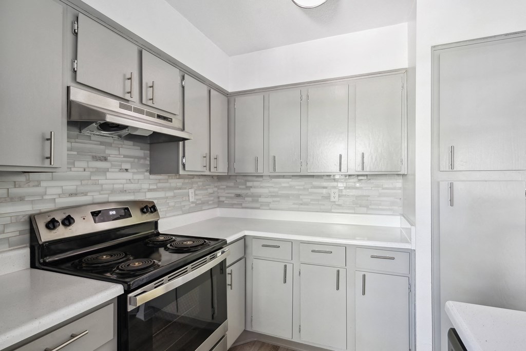 an empty kitchen with white cabinets and a stove