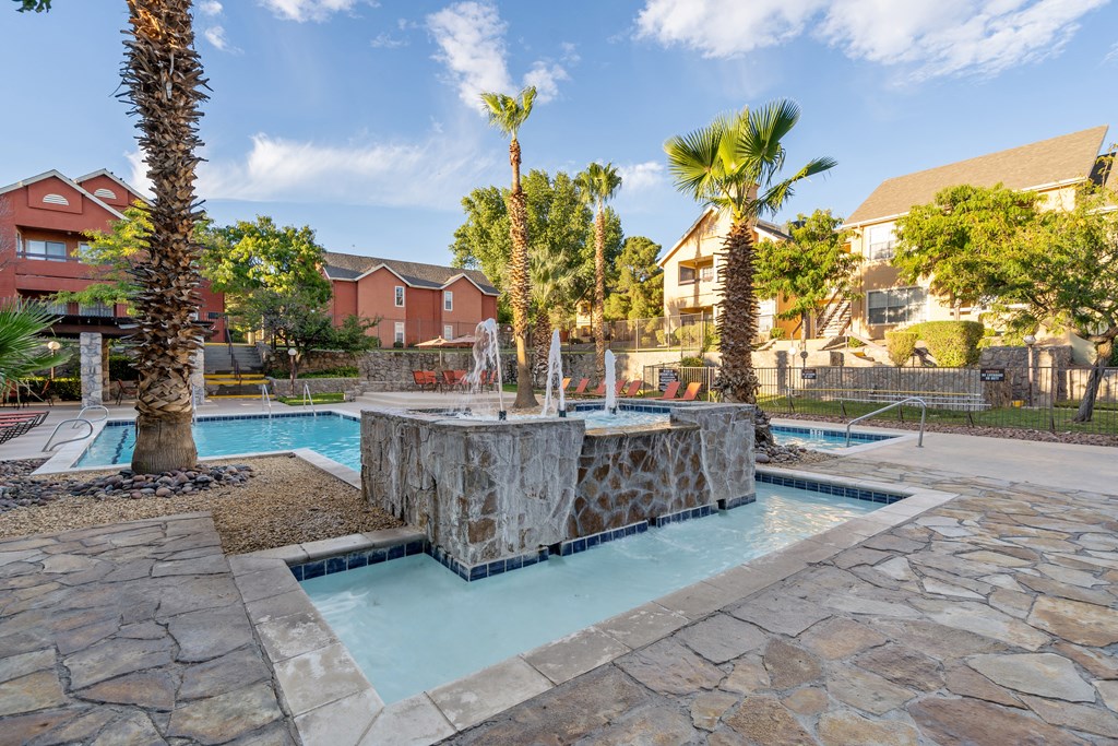 a swimming pool with a fountain and palm trees