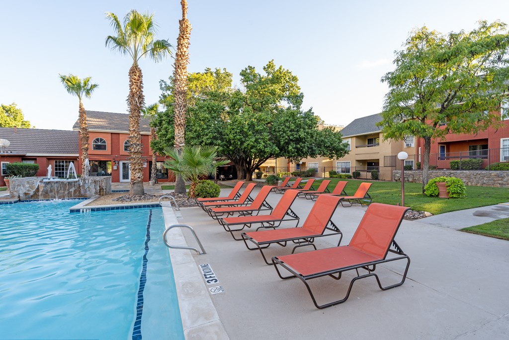 a row of red lounge chairs next to a swimming pool