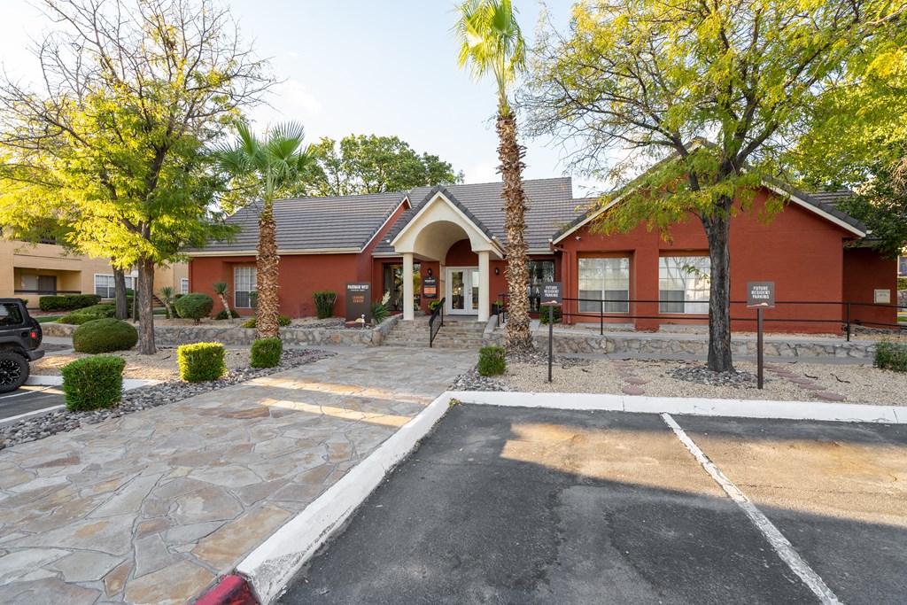 the front of a red building with a parking lot and palm trees