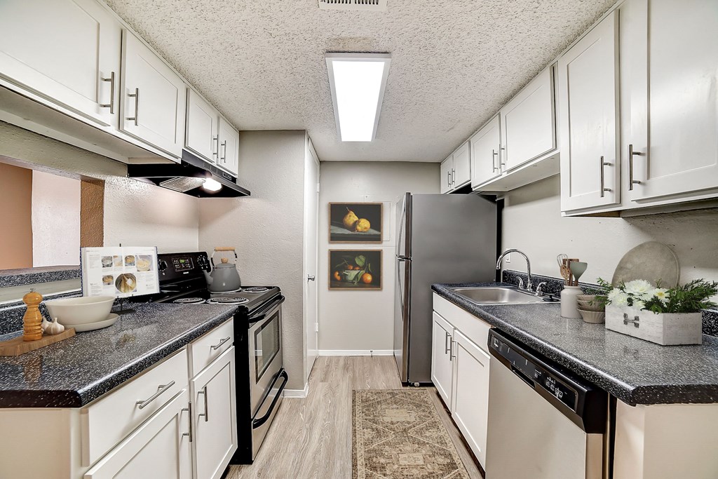 a kitchen with white cabinets and black countertops
