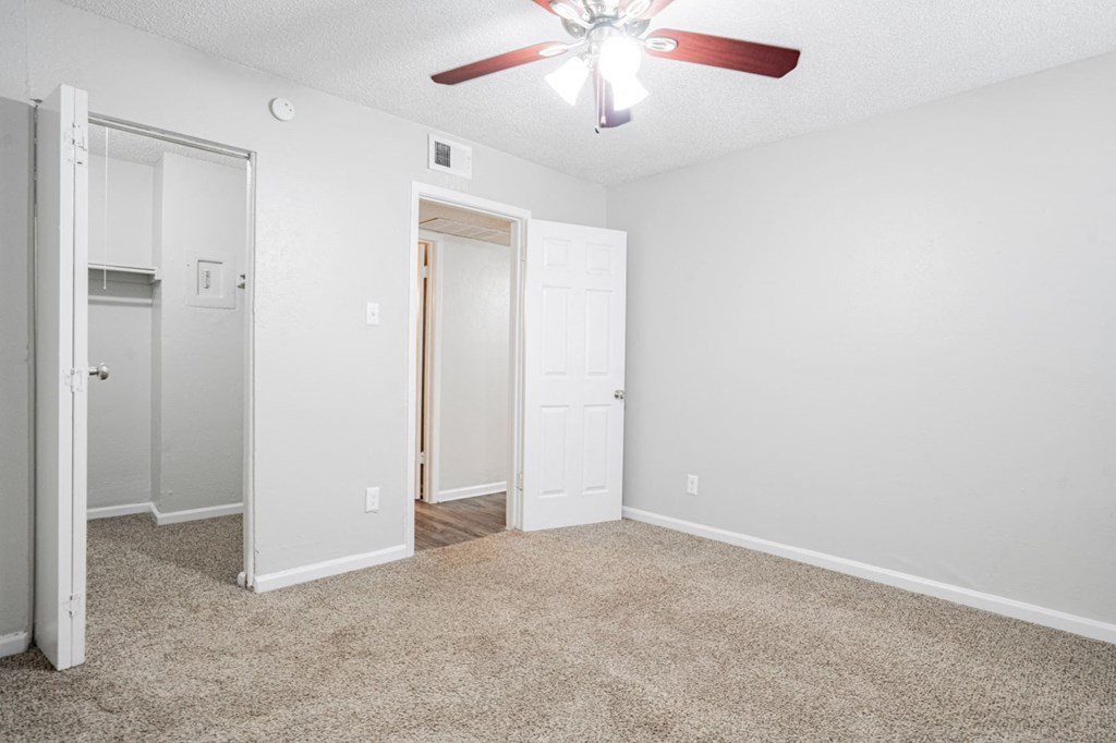 an empty living room with a ceiling fan and a closet