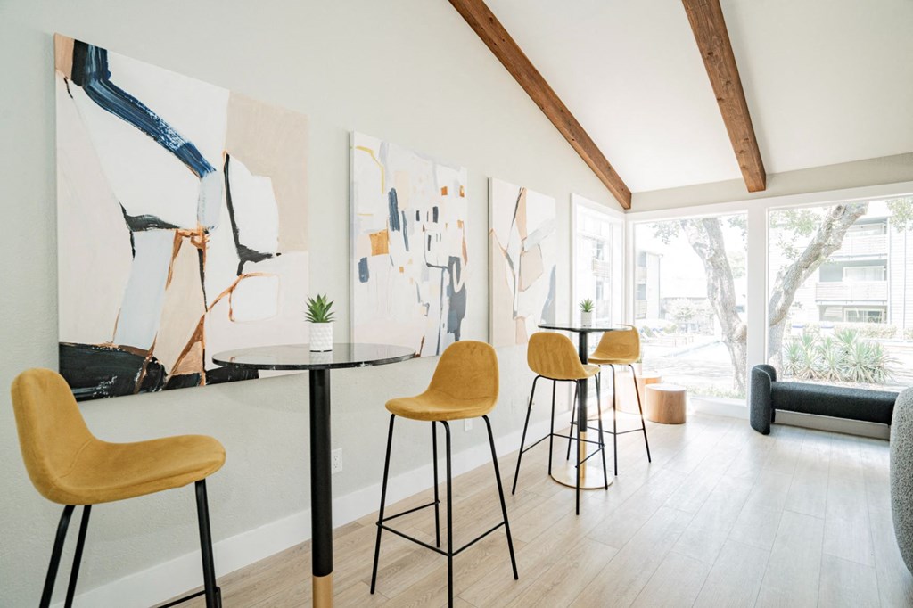 a dining area with tables and chairs and a large painting on the wall