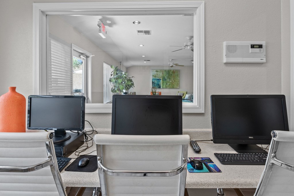 a computer lab with three computer monitors and a keyboard and mouse