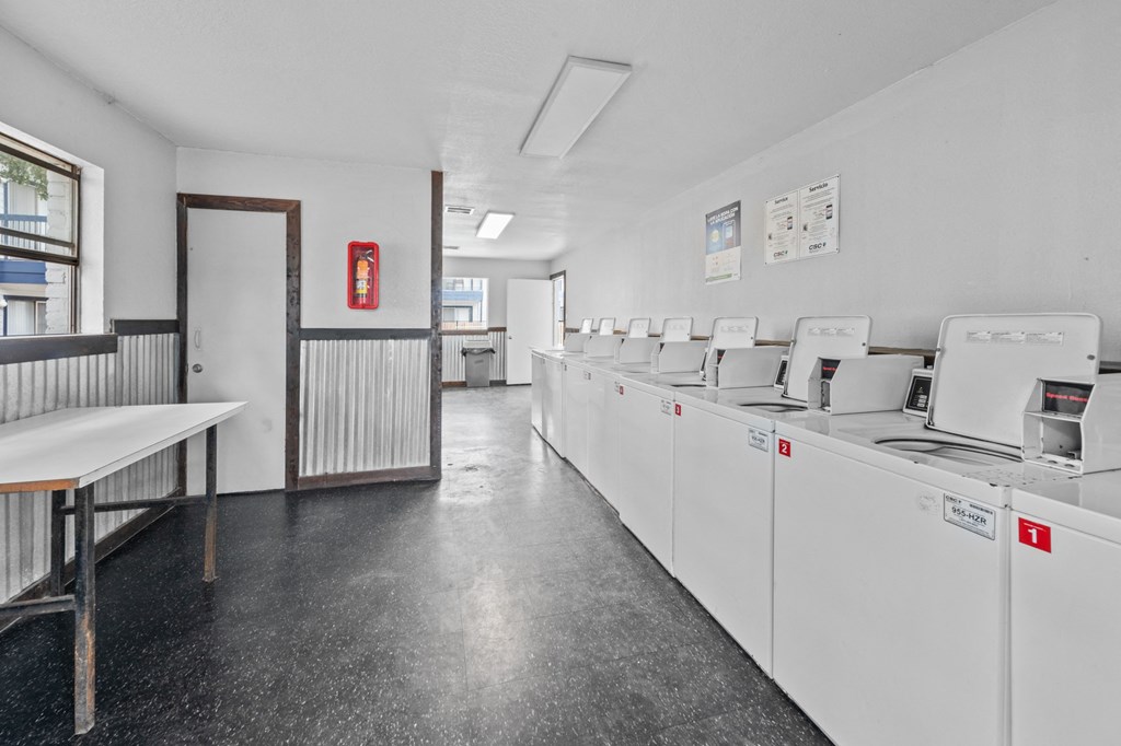 a laundry room with white walls and a black tiled floor