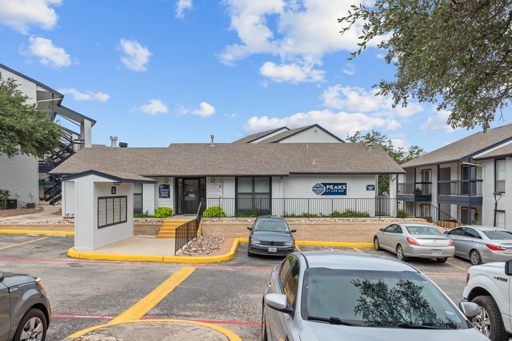 a white building with a gray roof and a parking lot in front of it
