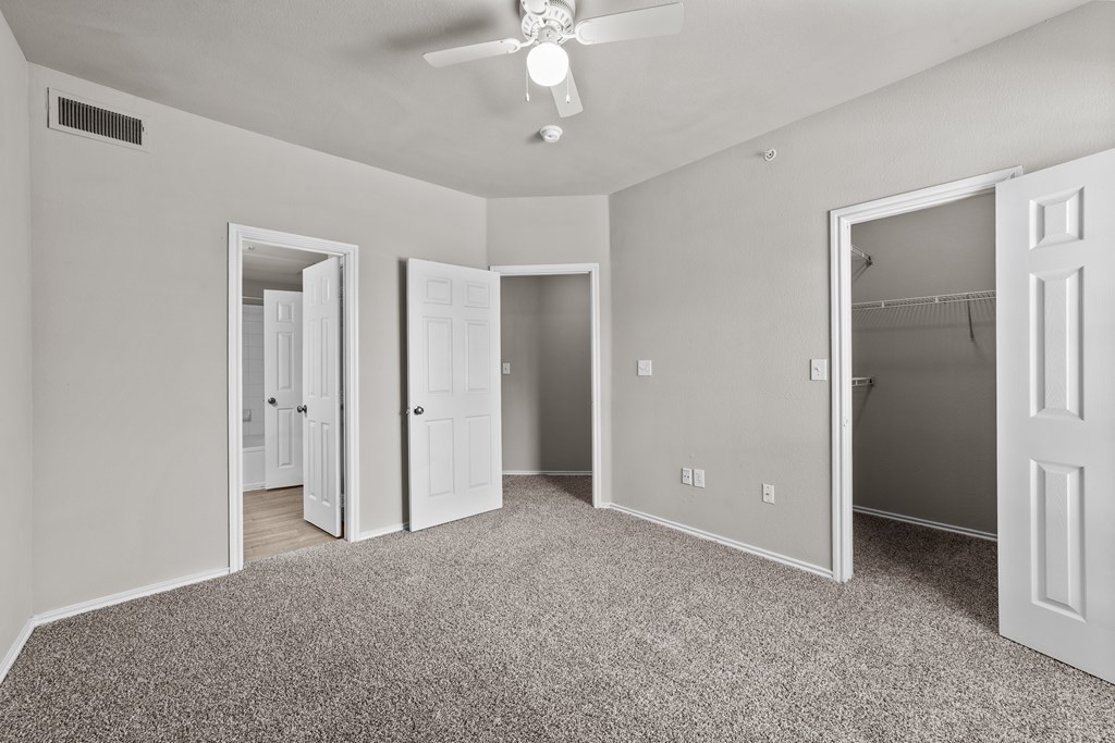 A room with a ceiling fan and carpeted floor.