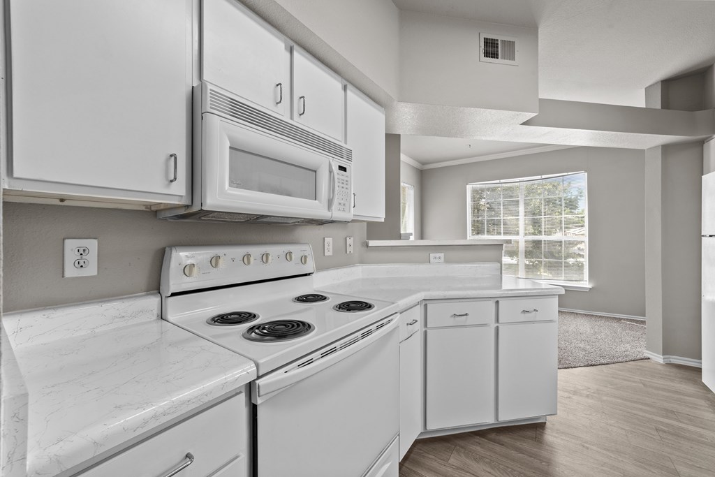 A white kitchen with a stove, oven, microwave, and refrigerator.