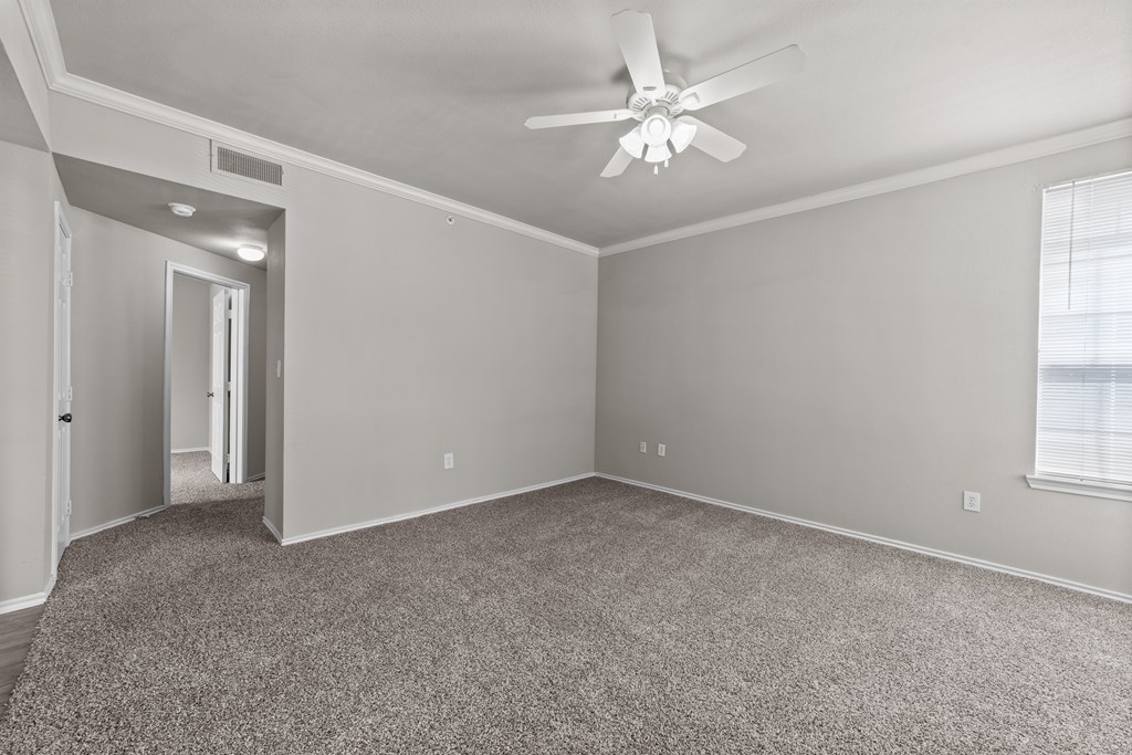 A room with a ceiling fan and carpeted floor.
