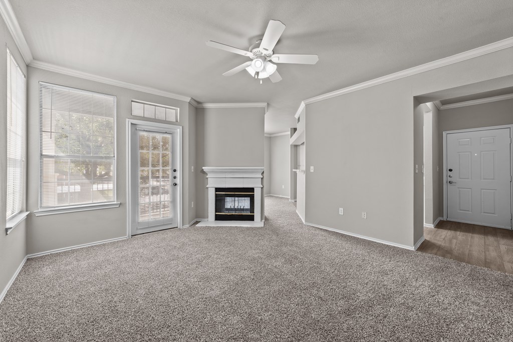 A spacious living room with a fireplace and a ceiling fan.