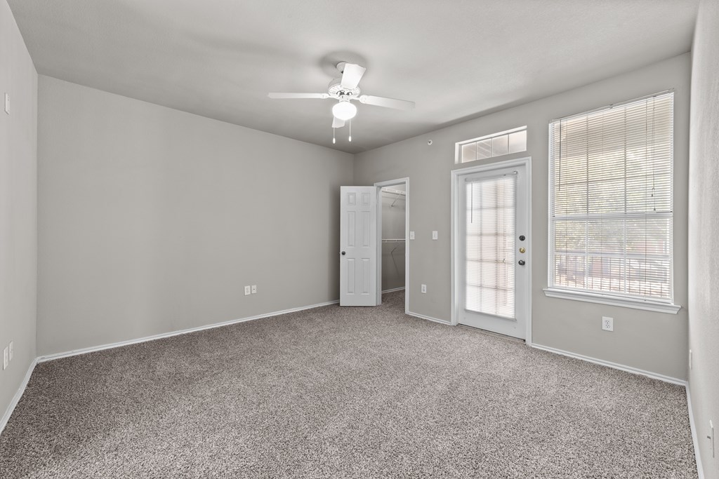 A spacious room with a carpeted floor and a ceiling fan.
