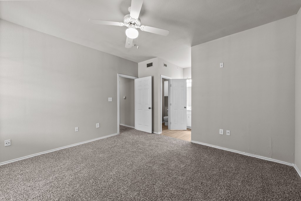 A room with a ceiling fan and carpeted floor.