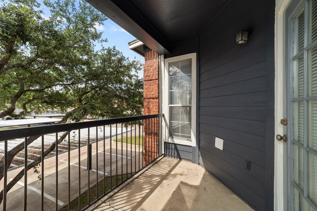 A balcony with a black railing and a brick pillar.