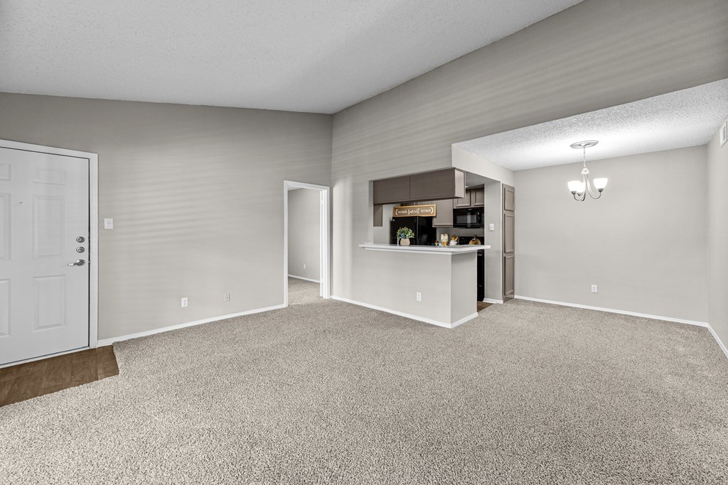 A spacious room with a carpeted floor and a white door.
