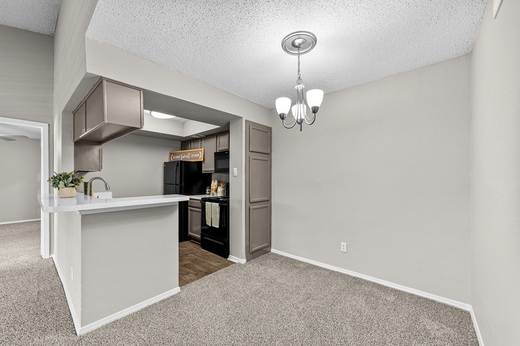 A kitchen area with a white counter and a refrigerator.