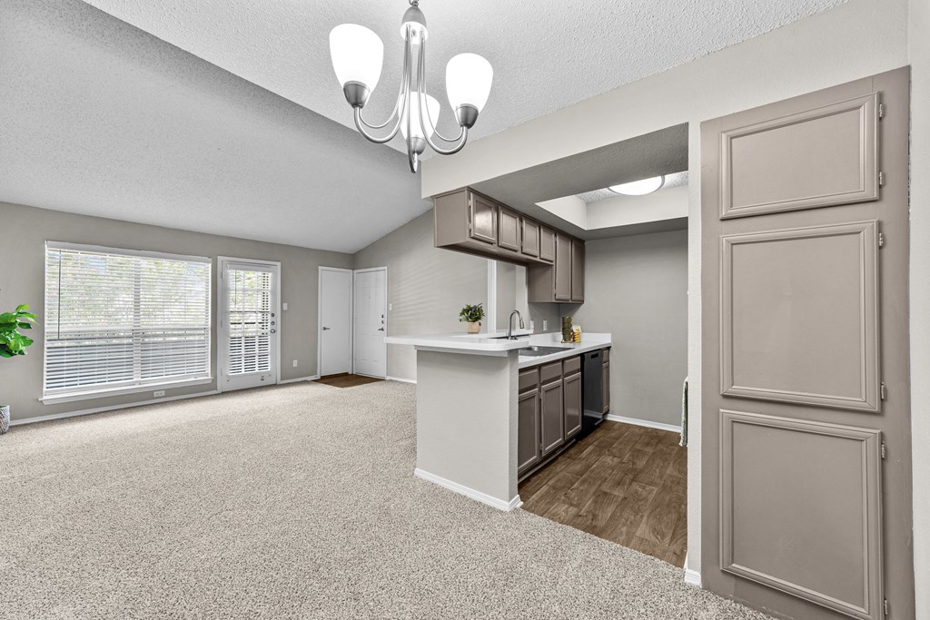 A spacious kitchen and living room with a chandelier and a potted plant.