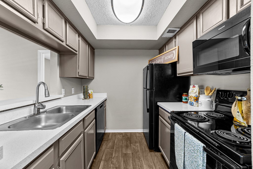 A kitchen with a black refrigerator and a white sink.